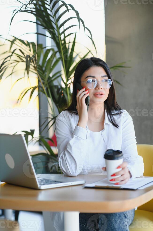 Beautiful Caucasian woman dreaming about something while sitting with portable net-book in modern cafe bar, young charming female freelancer thinking about new ideas during work on laptop computer photo