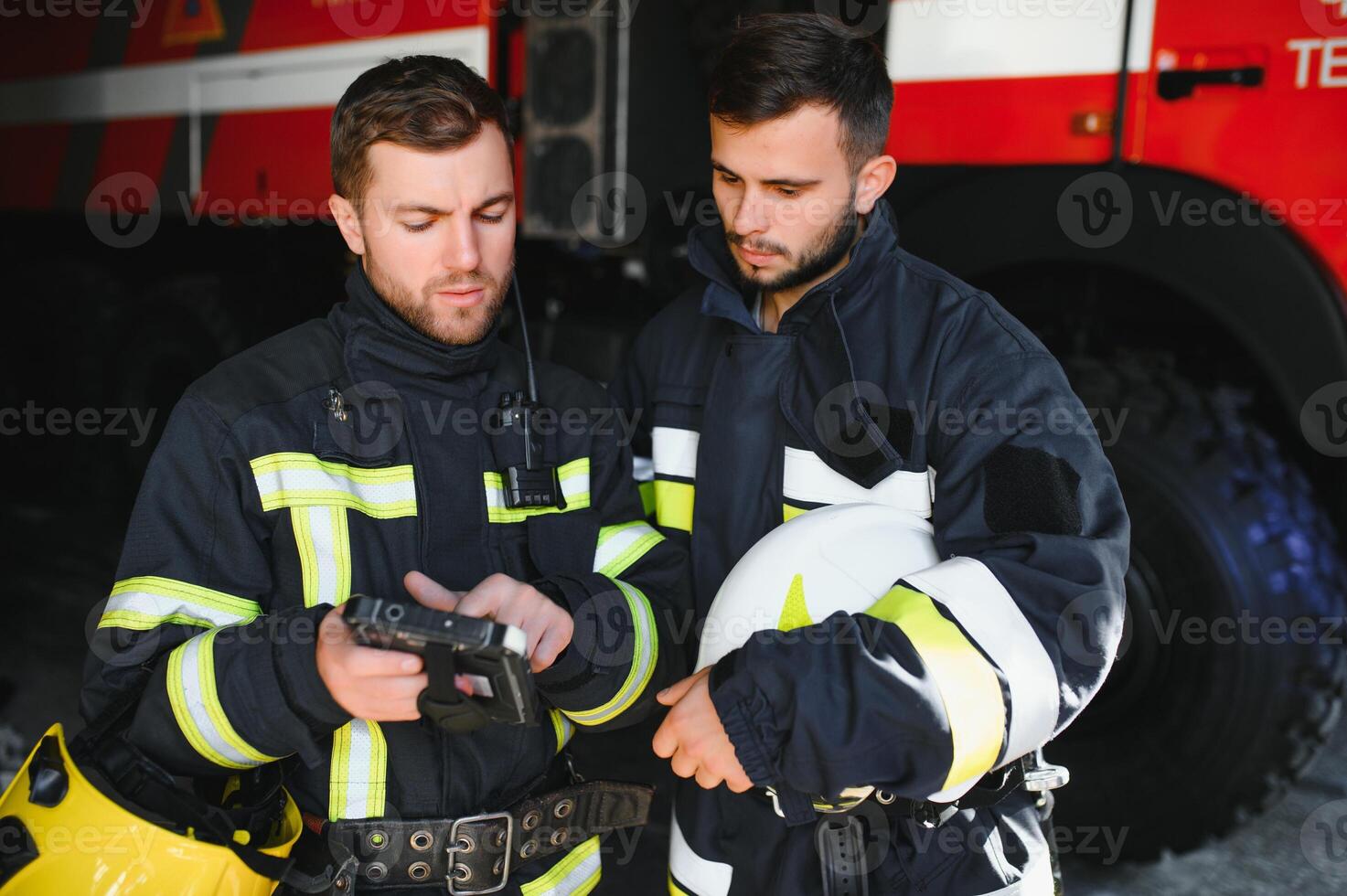 Portrait of two firefighters in fire fighting operation, fireman in protective clothing and helmet using tablet computer in action fighting photo