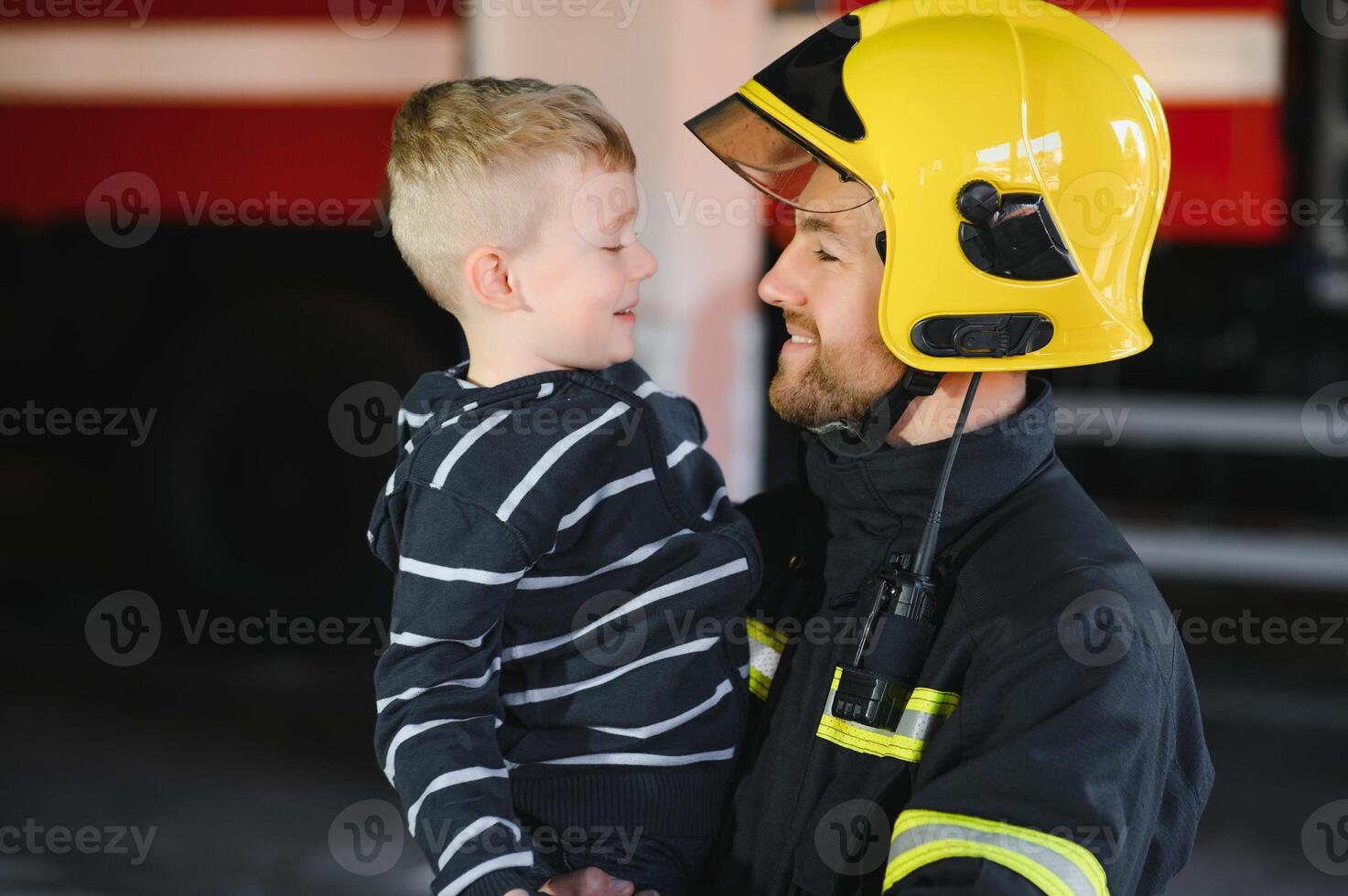 Portrait of rescued little boy with firefighter man standing near fire truck. Firefighter in fire fighting operation. photo