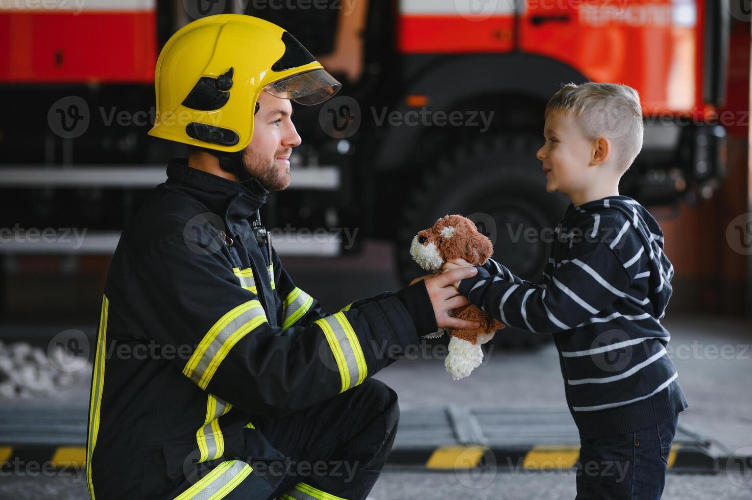 Portrait of rescued little boy with firefighter man standing near fire truck. Firefighter in fire fighting operation. photo
