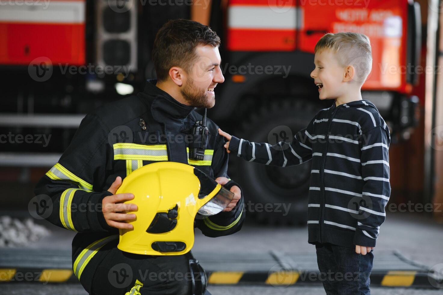 Portrait of rescued little boy with firefighter man standing near fire truck. Firefighter in fire fighting operation. photo