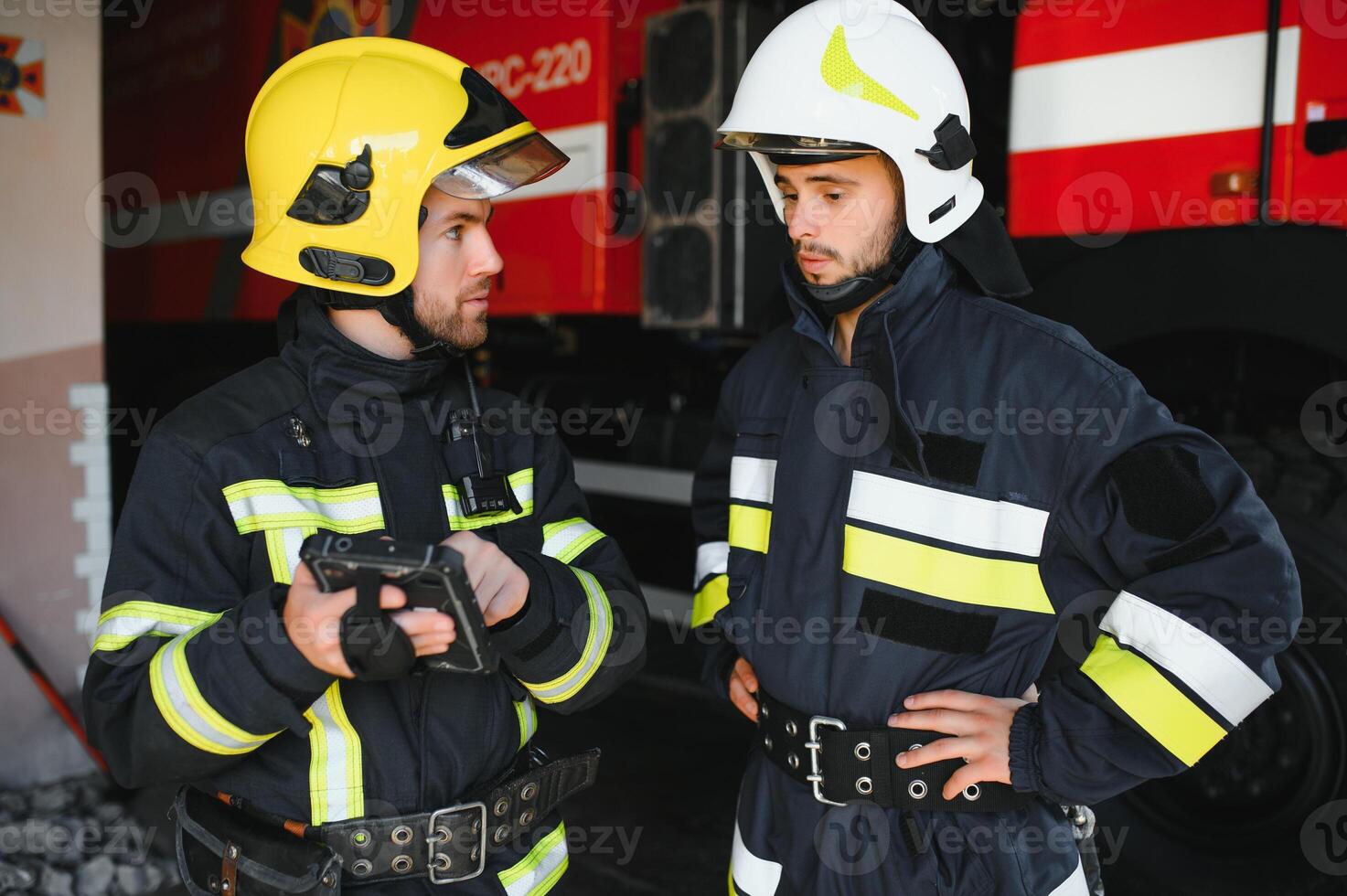 Portrait of two firefighters in fire fighting operation, fireman in protective clothing and helmet using tablet computer in action fighting photo