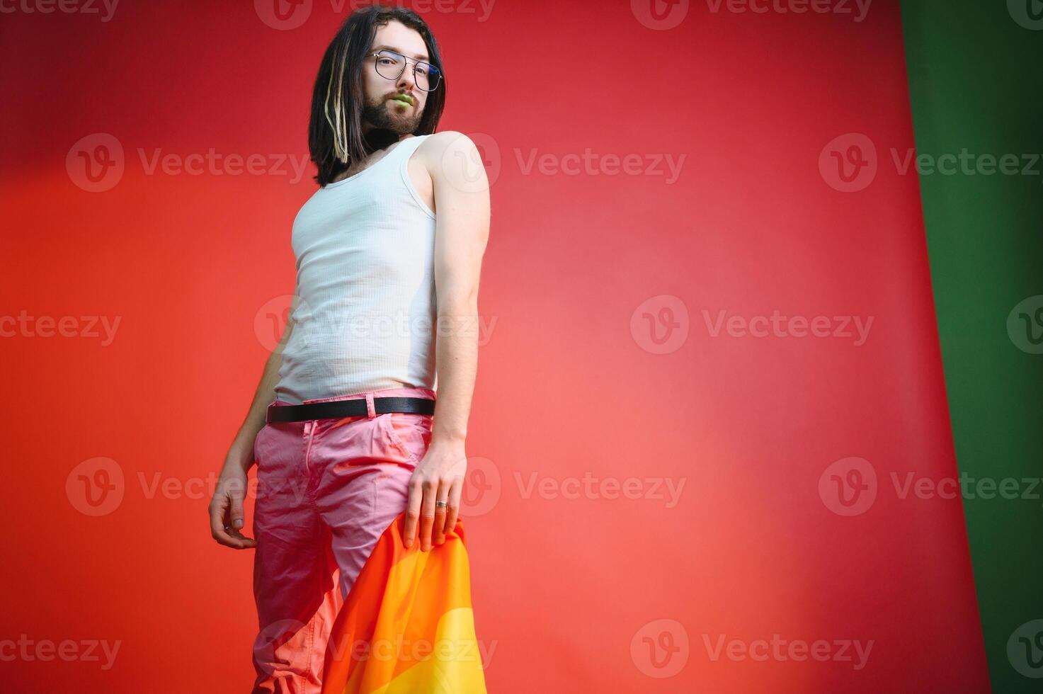 Gay man hold rainbow striped flag isolated on colored background studio portrait. People lifestyle fashion lgbtq concept photo
