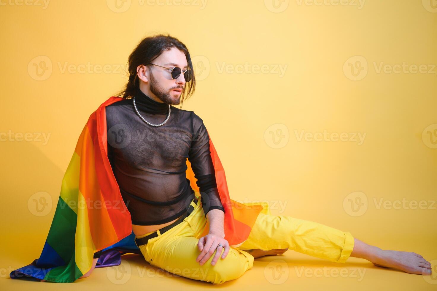 gay man with a gay pride flag smiling and looking away on yellow background photo