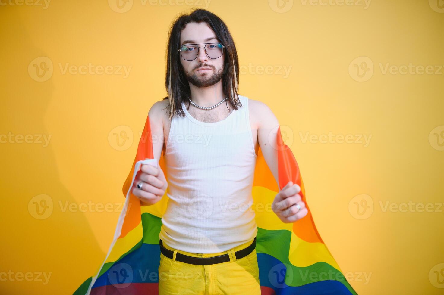 Handsome young man with pride movement LGBT Rainbow flag on shoulder against white background. Man with a gay pride flag. photo