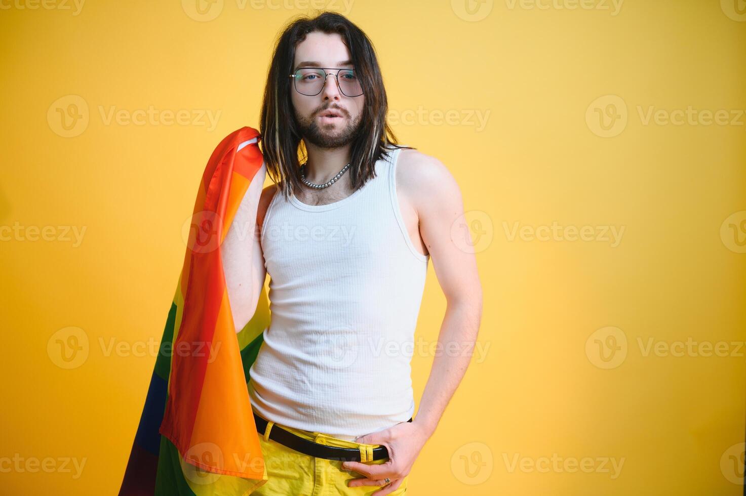 Gay man hold rainbow striped flag isolated on colored background studio portrait. People lifestyle fashion lgbtq concept photo