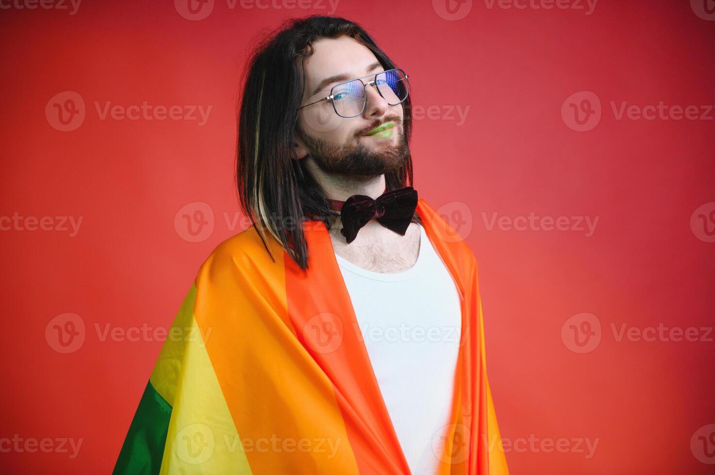 Handsome young man with pride movement LGBT Rainbow flag on shoulder against white background. Man with a gay pride flag. photo