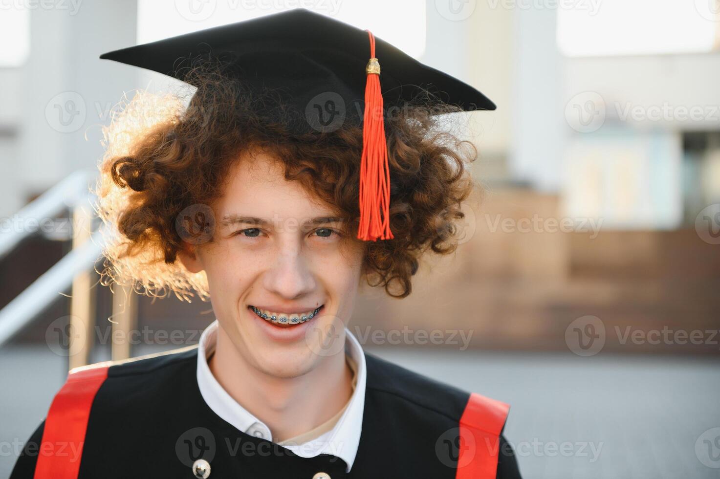 Portrait of a happy Caucasian male student wearing a gown and a hat graduating from high school college looking at camera smiling. photo