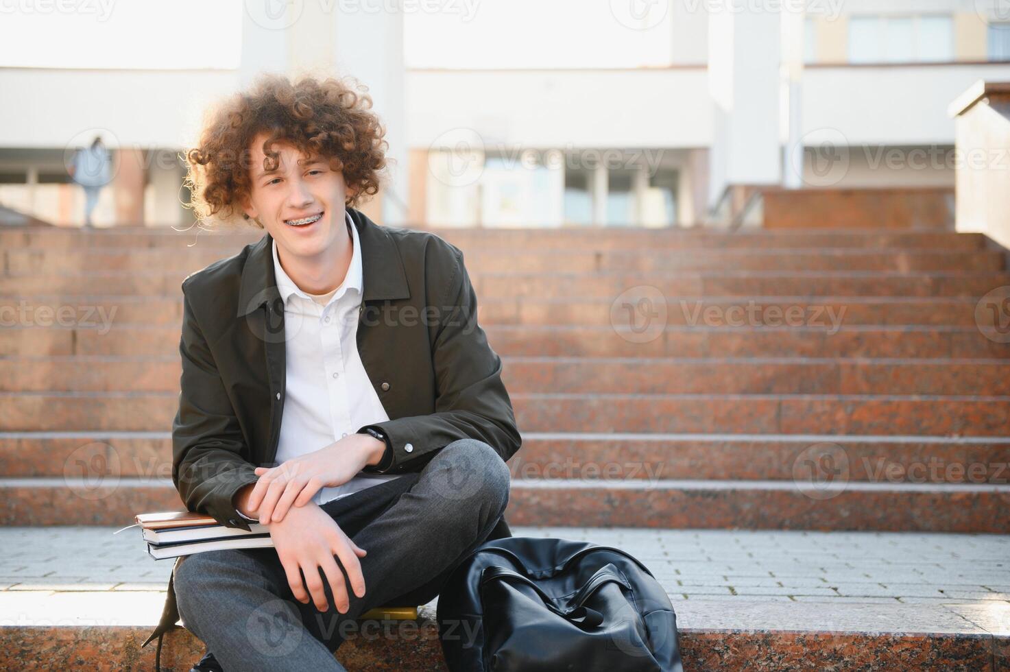 University.Smiling young student man holding a book and a bag on a university background .Young smiling student outdoors Life style.City.Student. photo