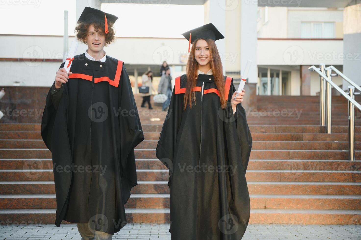 Happy friends on graduation day. Portrait of two cheerful joyful students standing near university building. photo