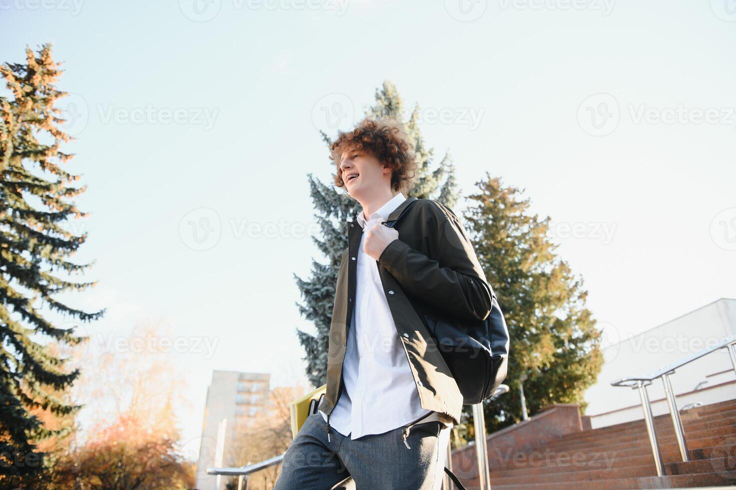 Portrait of a cheerful college student standing outside with back photo