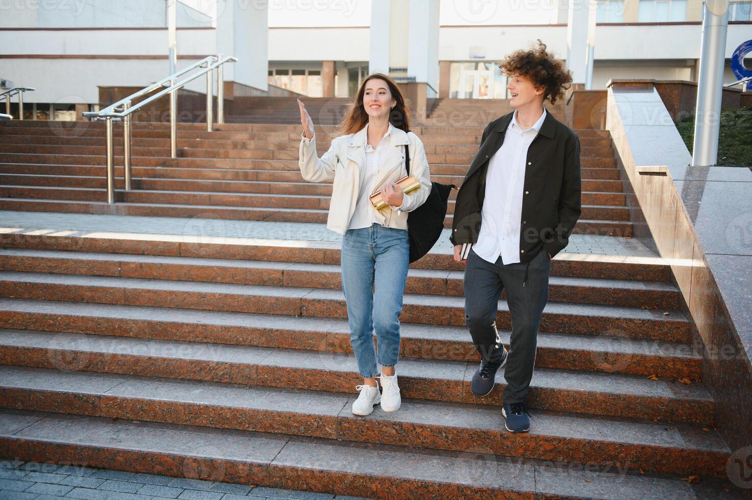 Front view of two students walking and talking in an university campus. photo