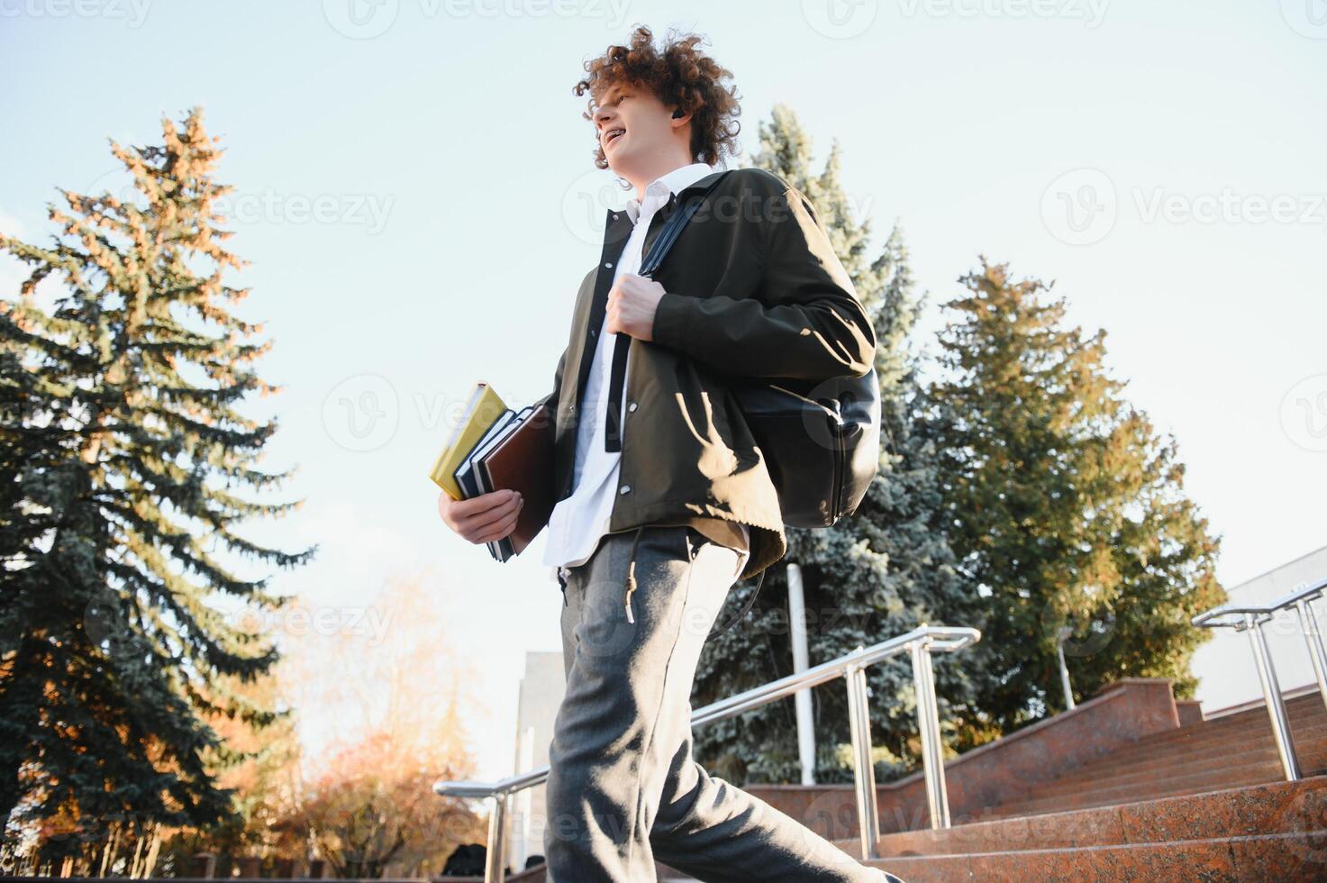 University.Smiling young student man holding a book and a bag on a university background .Young smiling student outdoors Life style.City.Student. photo