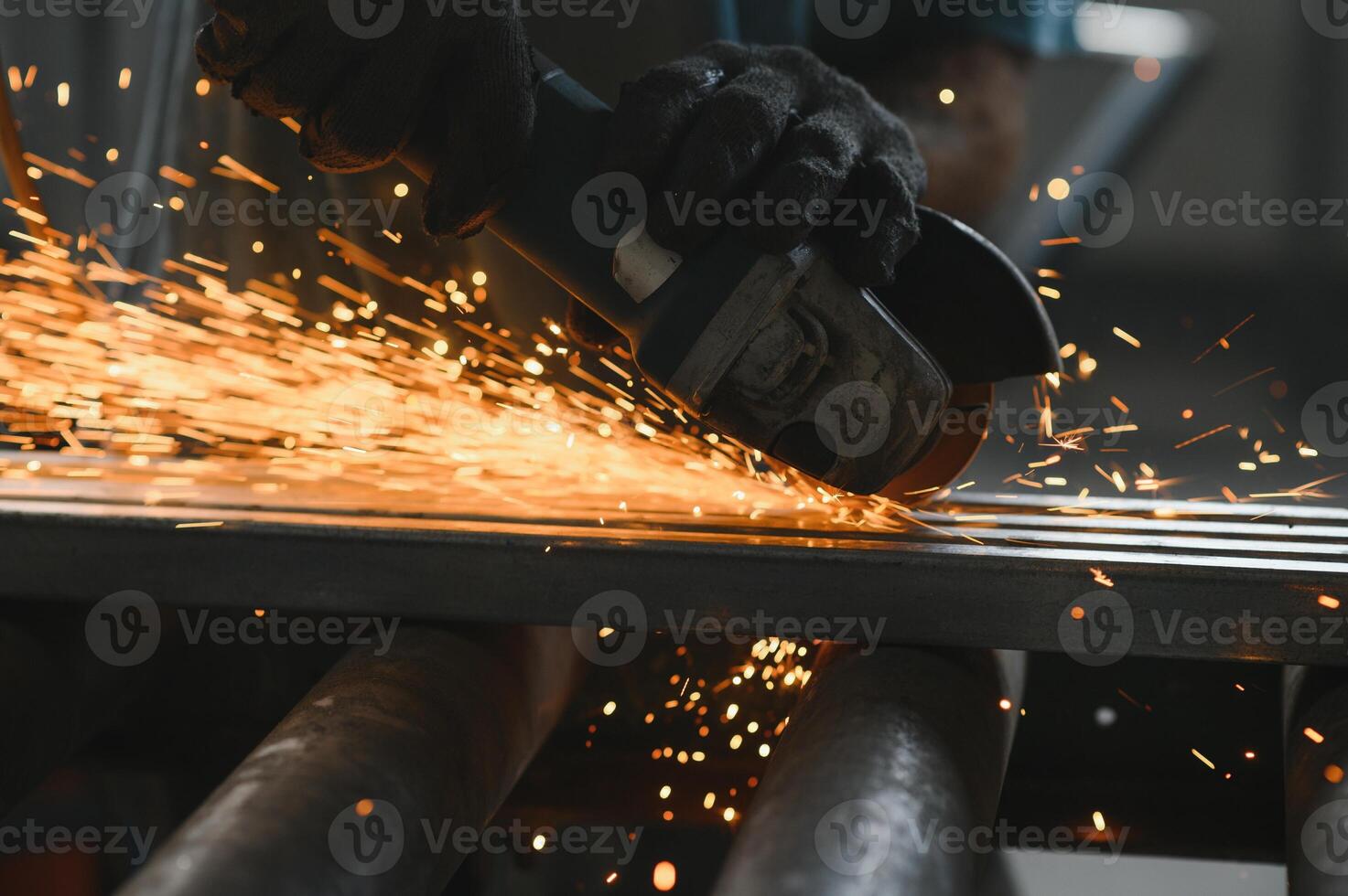 Heavy Industry Engineering Factory Interior with Industrial Worker Using Angle Grinder and Cutting a Metal Tube. Contractor in Safety Uniform and Hard Hat Manufacturing Metal Structures. photo