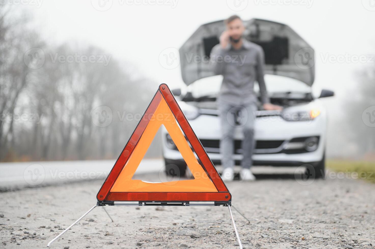 Sad driver calling car service, opening hood, having engine problem standing near broken car on the road. Car breakdown concept photo