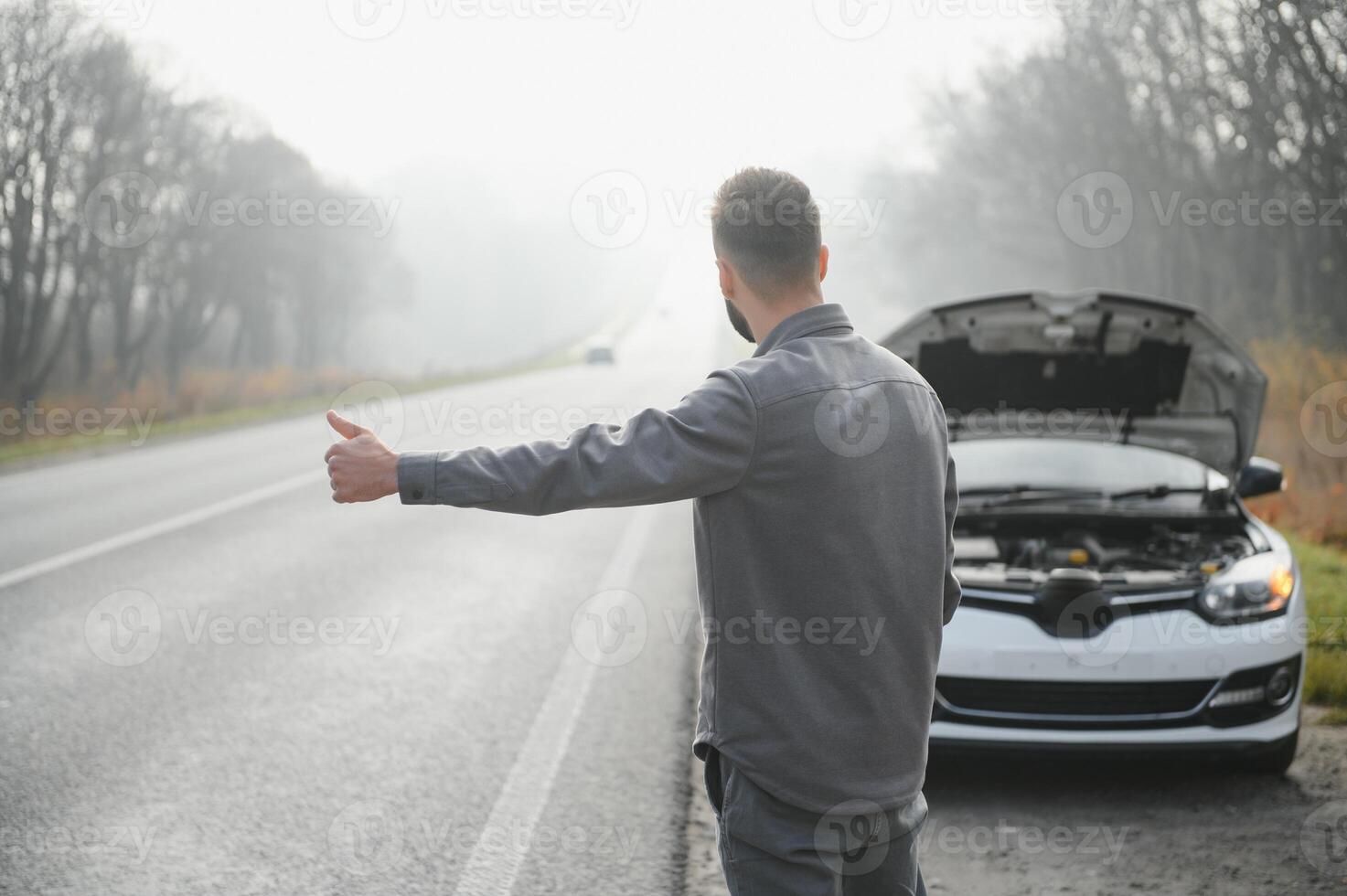 Sad man near broken car searching help in field photo