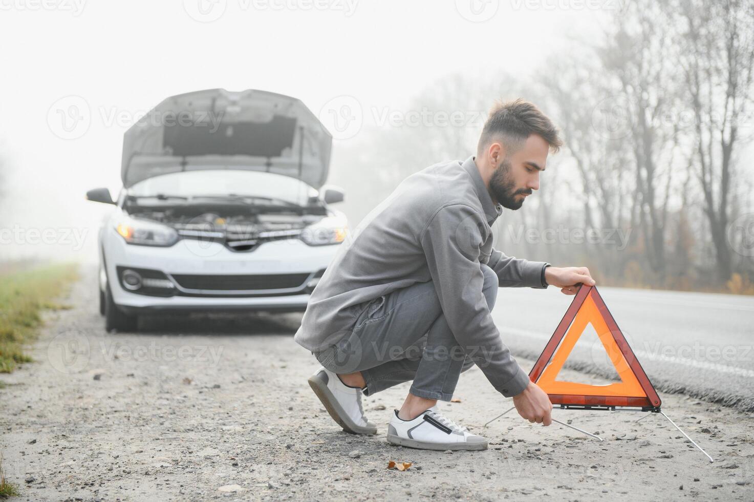 Sad driver having engine problem standing near broken car on the road. Car breakdown concept photo
