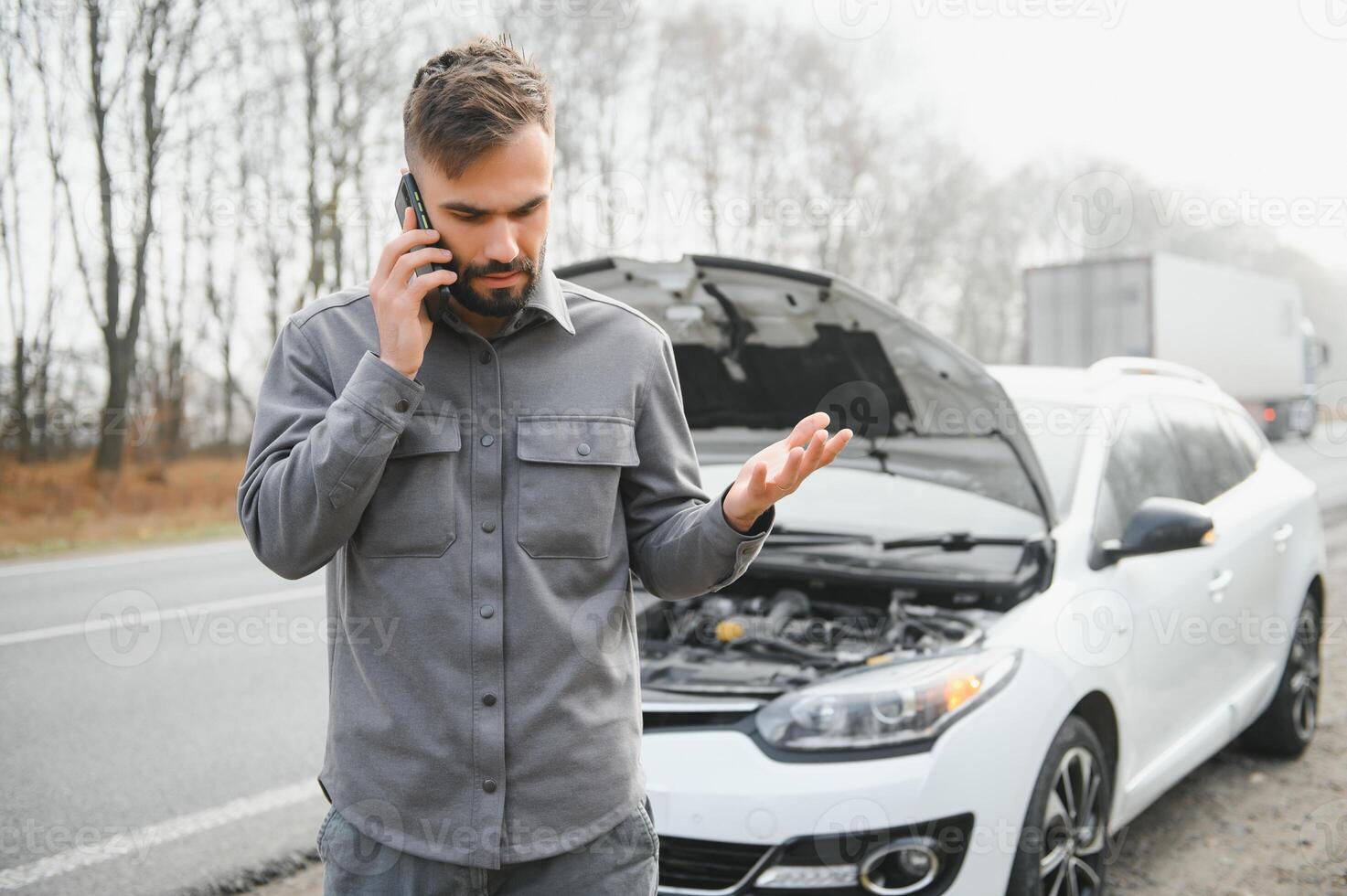 Man use a cellphone call garage in front of the open hood of a broken car on the road in the forest. Car breakdown concept. photo