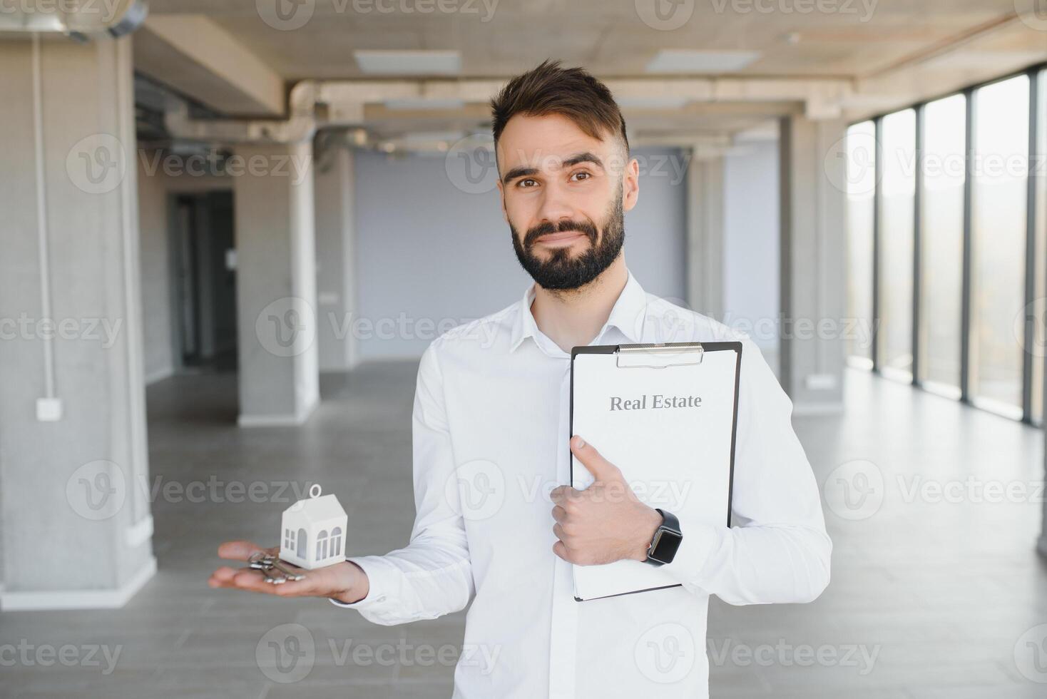 Real estate agent holding key on blurred background, closeup photo