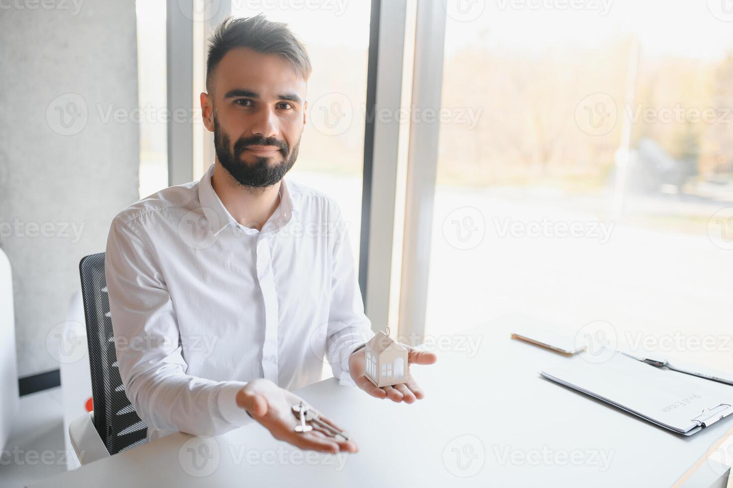 Portrait of a young realtor in the office at the table. Real estate sales concept. photo