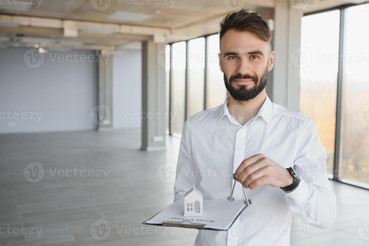 Real estate agent holding key on blurred background, closeup photo
