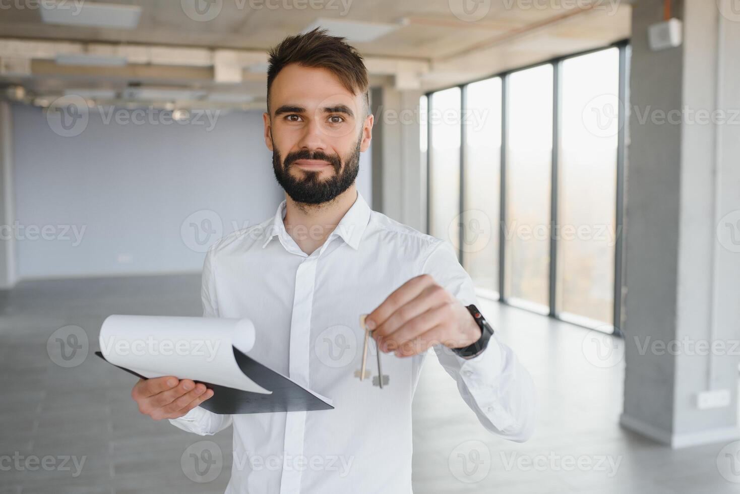 Real estate agent holding key on blurred background, closeup photo