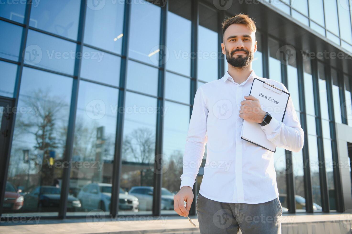 Businessman or real estate agent ready to discuss business and stands against new building photo