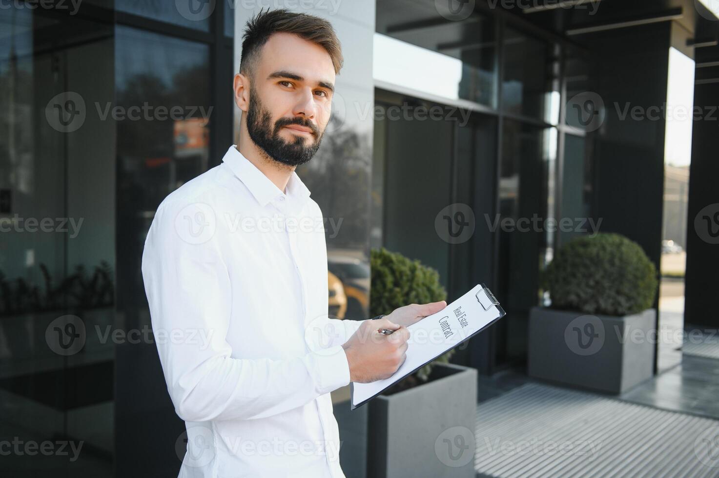Businessman or real estate agent ready to discuss business and stands against new building photo