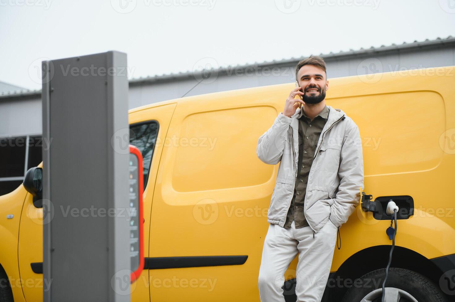 Man on the electric cars charge station at daytime. photo