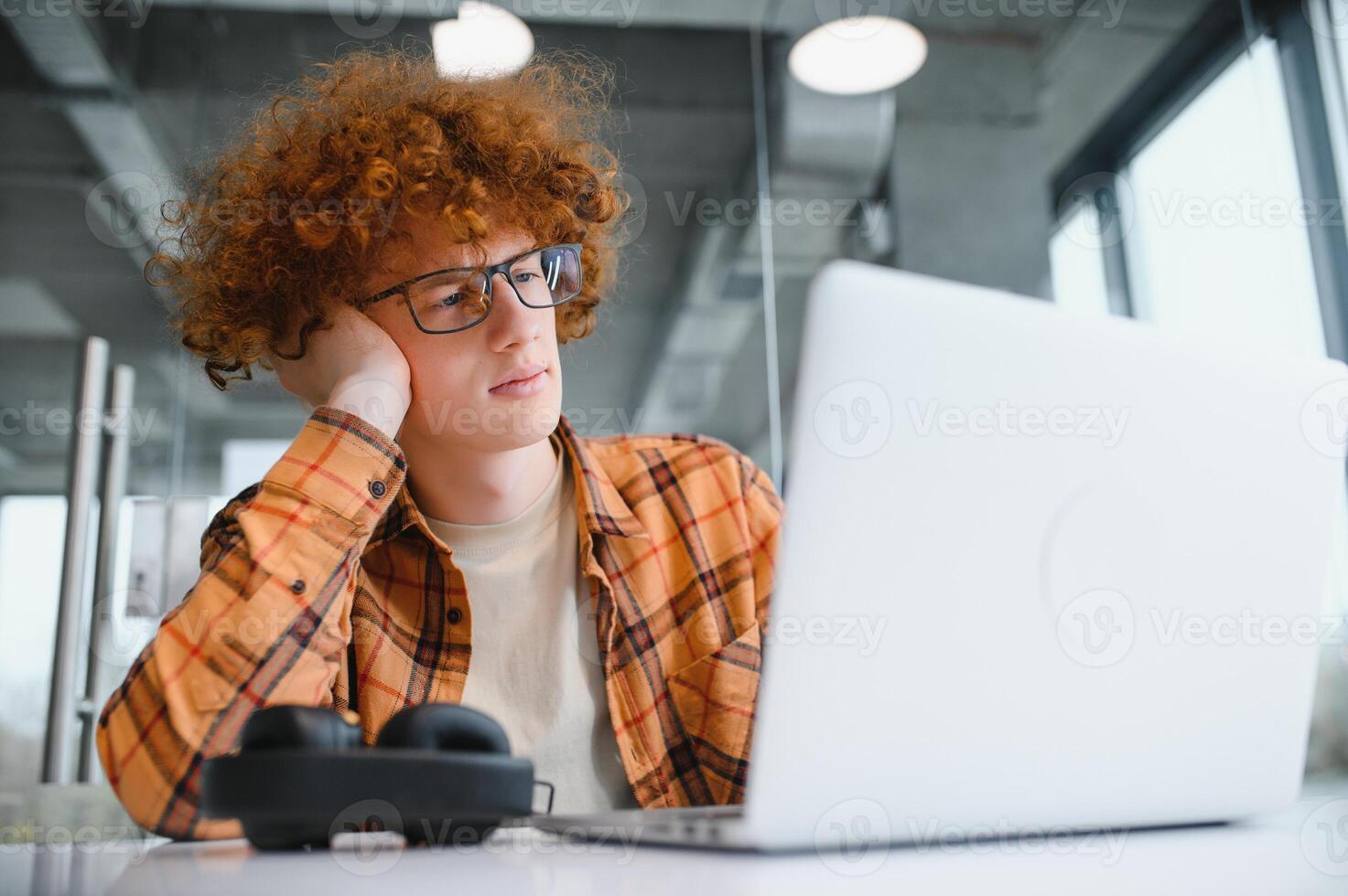 Cheerful male freelancer browsing funny content while networking in social media using netbook technology in street cafe, happy hipster guy enjoying free time for online blogging via laptop photo
