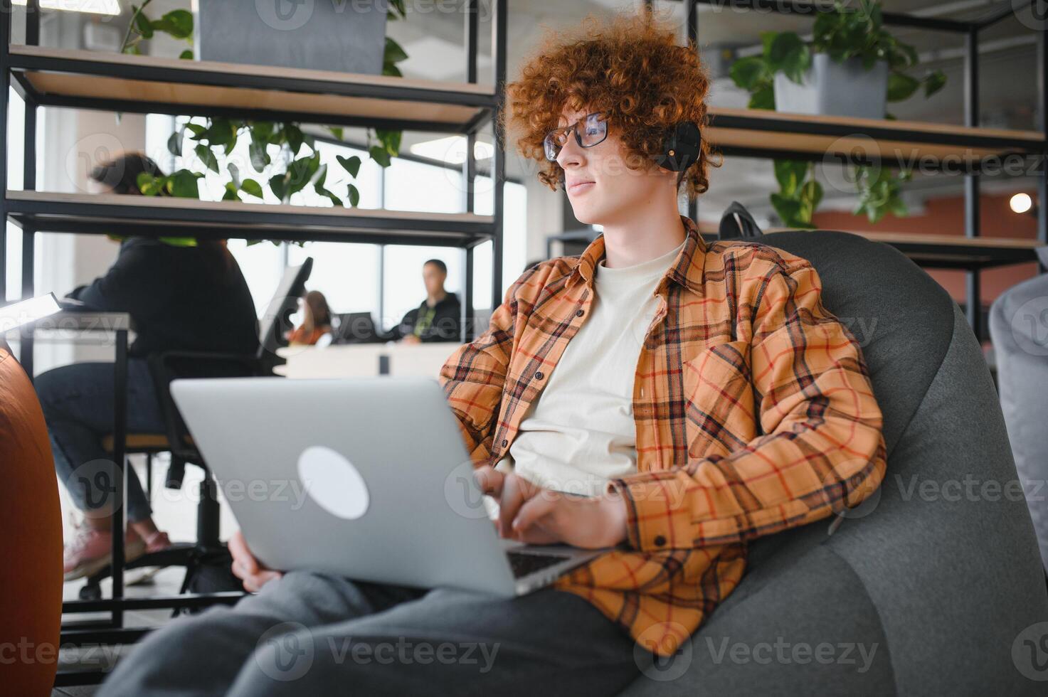Portrait of Caucasian male freelancer in trendy apparel sitting at cafeteria table and doing remote work for programming design of public website, skilled software developer posing in coworking space. photo