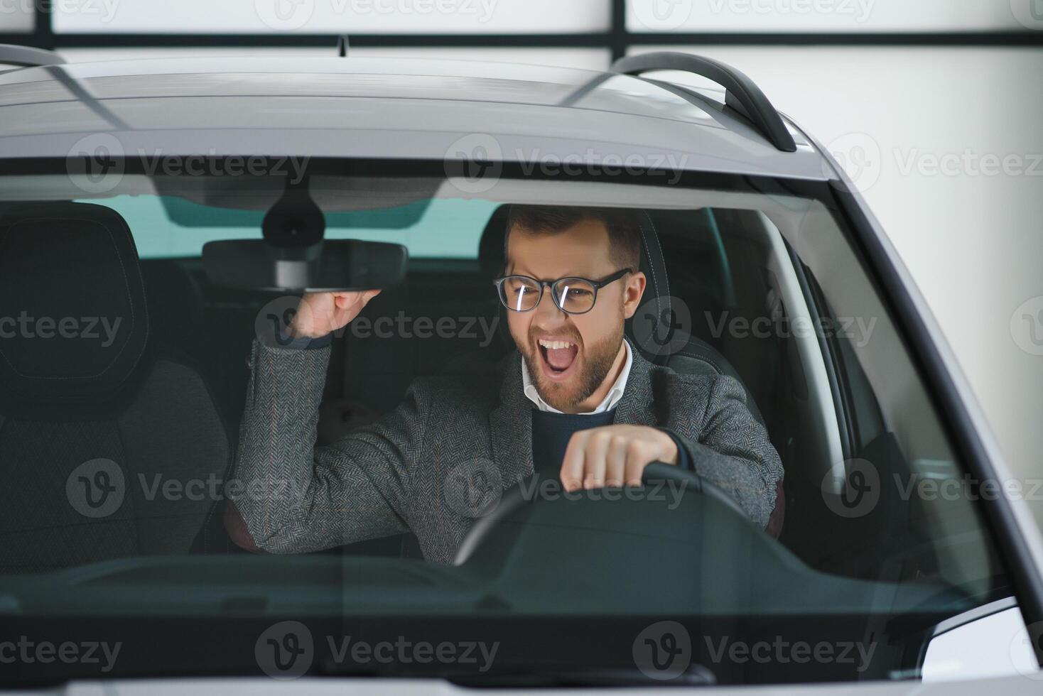 Visiting car dealership. Handsome bearded man is stroking his new car and smiling photo