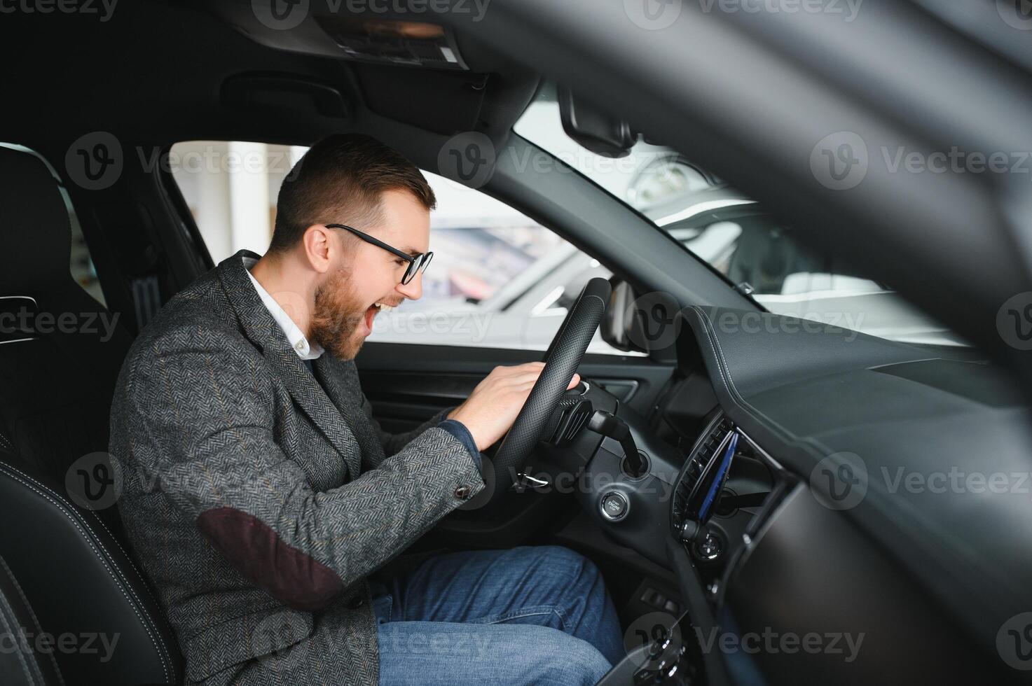 Visiting car dealership. Handsome bearded man is stroking his new car and smiling photo