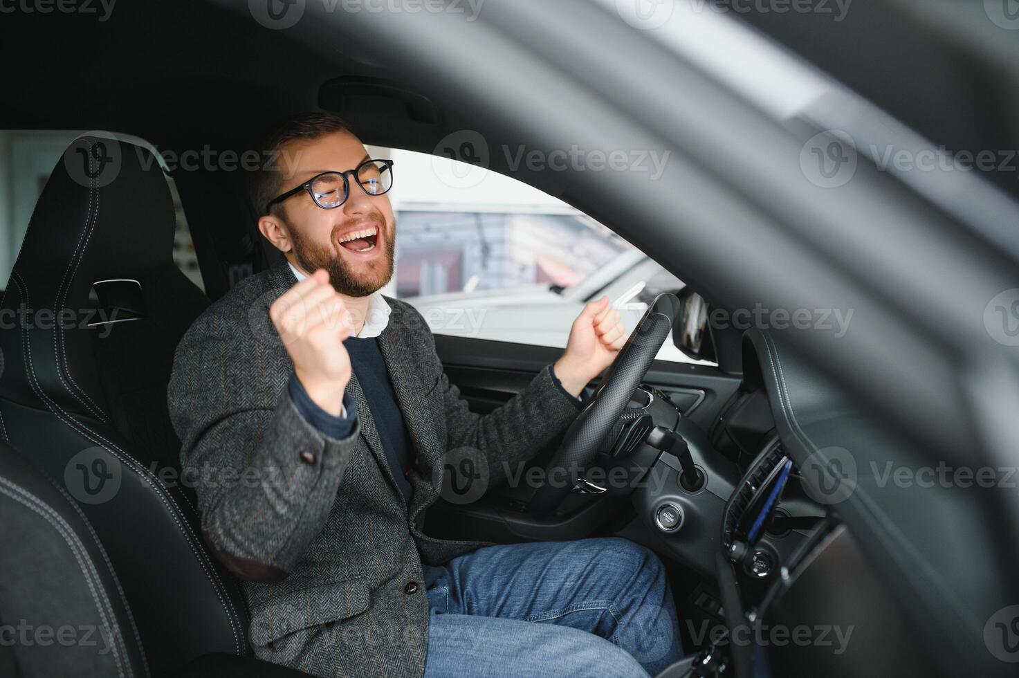 Visiting car dealership. Handsome bearded man is stroking his new car and smiling photo