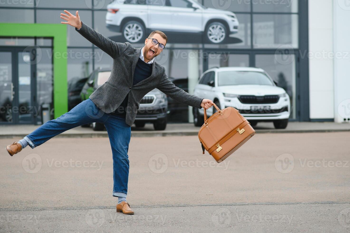 Happy buyer near the car in front of the modern avtosalon building photo