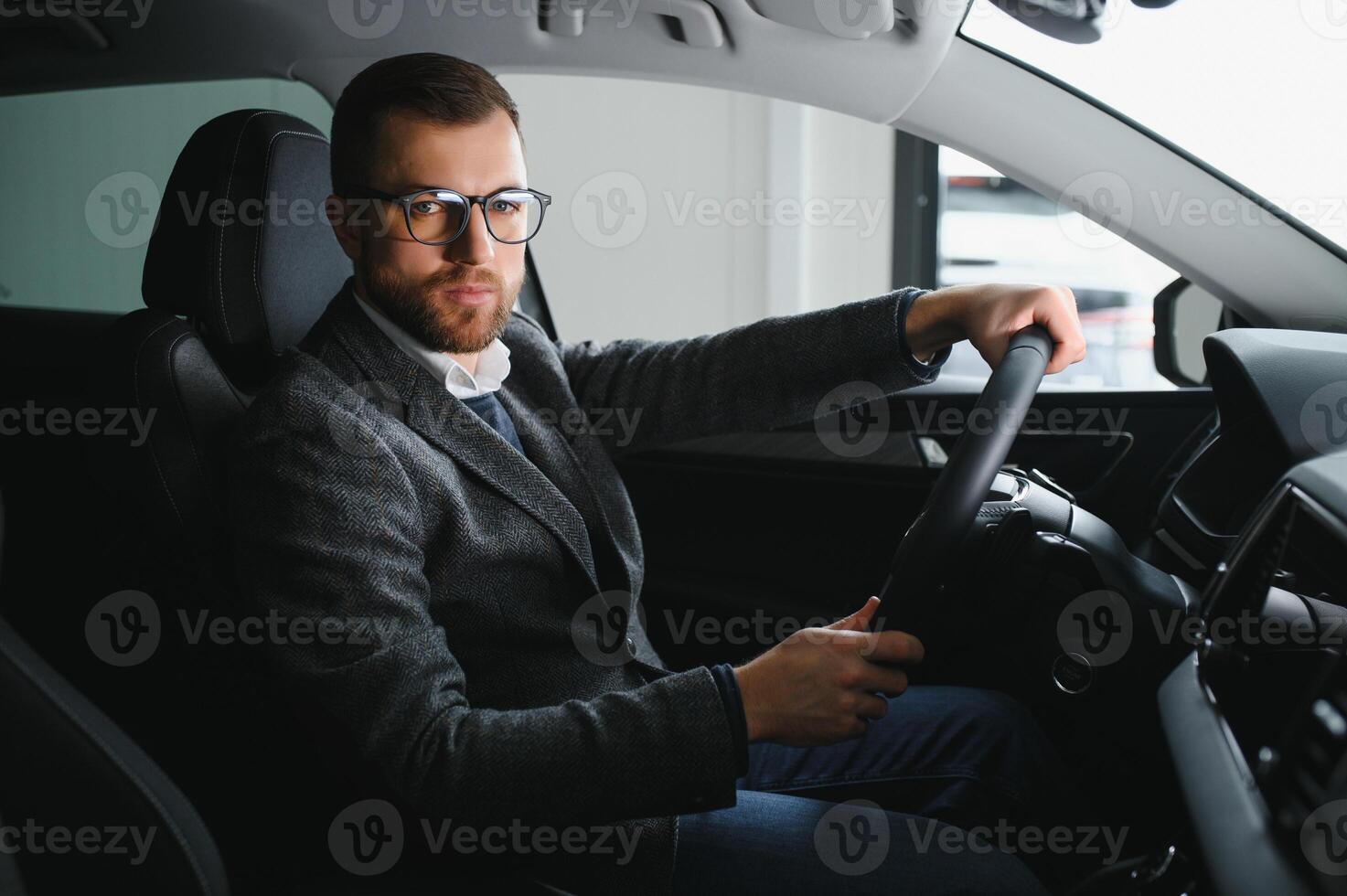 Handsome businessman driving car to airport, going on business side view, copy space. Happy man in stylish suit going to business meeting in the morning, driving his luxury car, shot from cabin. photo