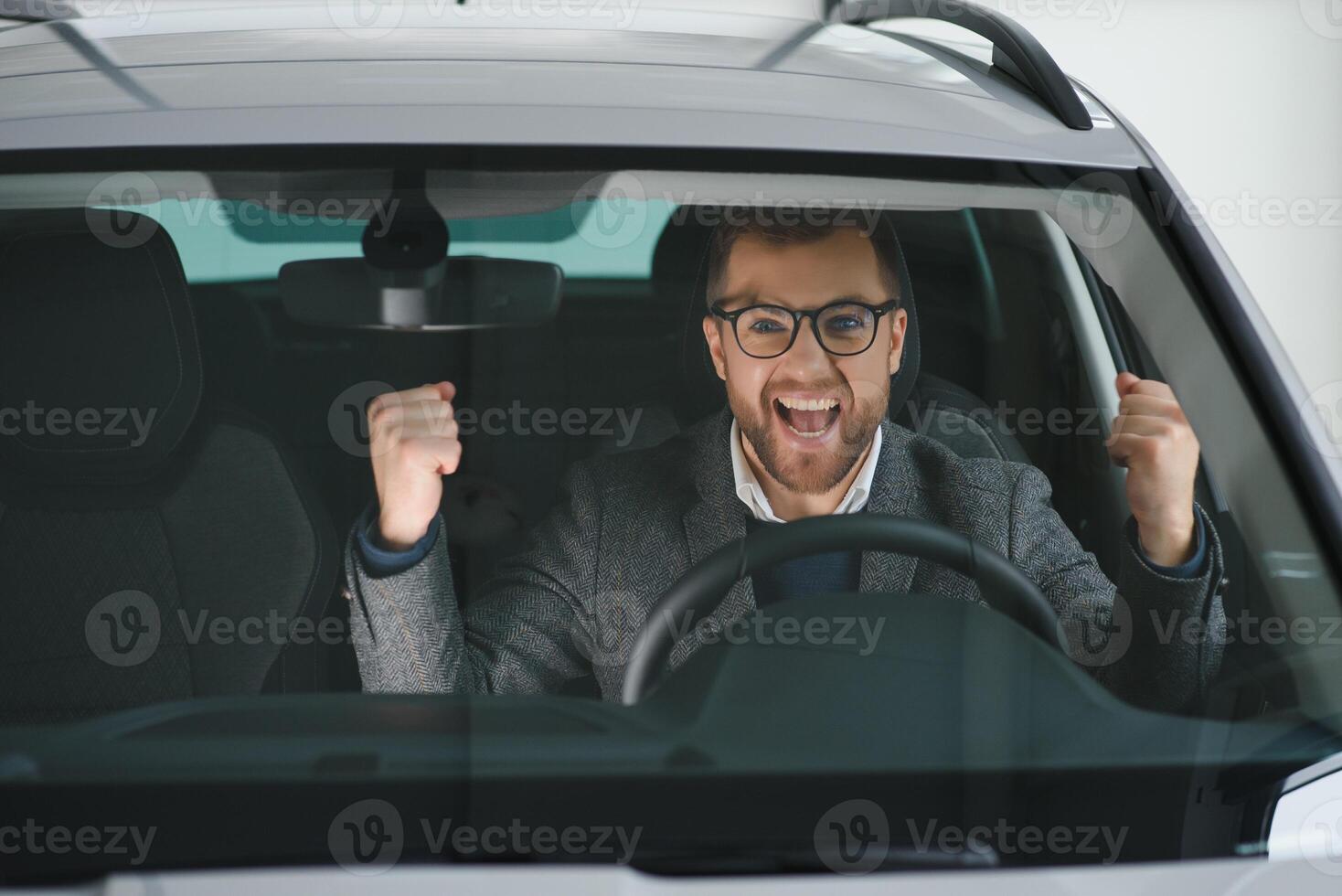 Visiting car dealership. Handsome bearded man is stroking his new car and smiling photo