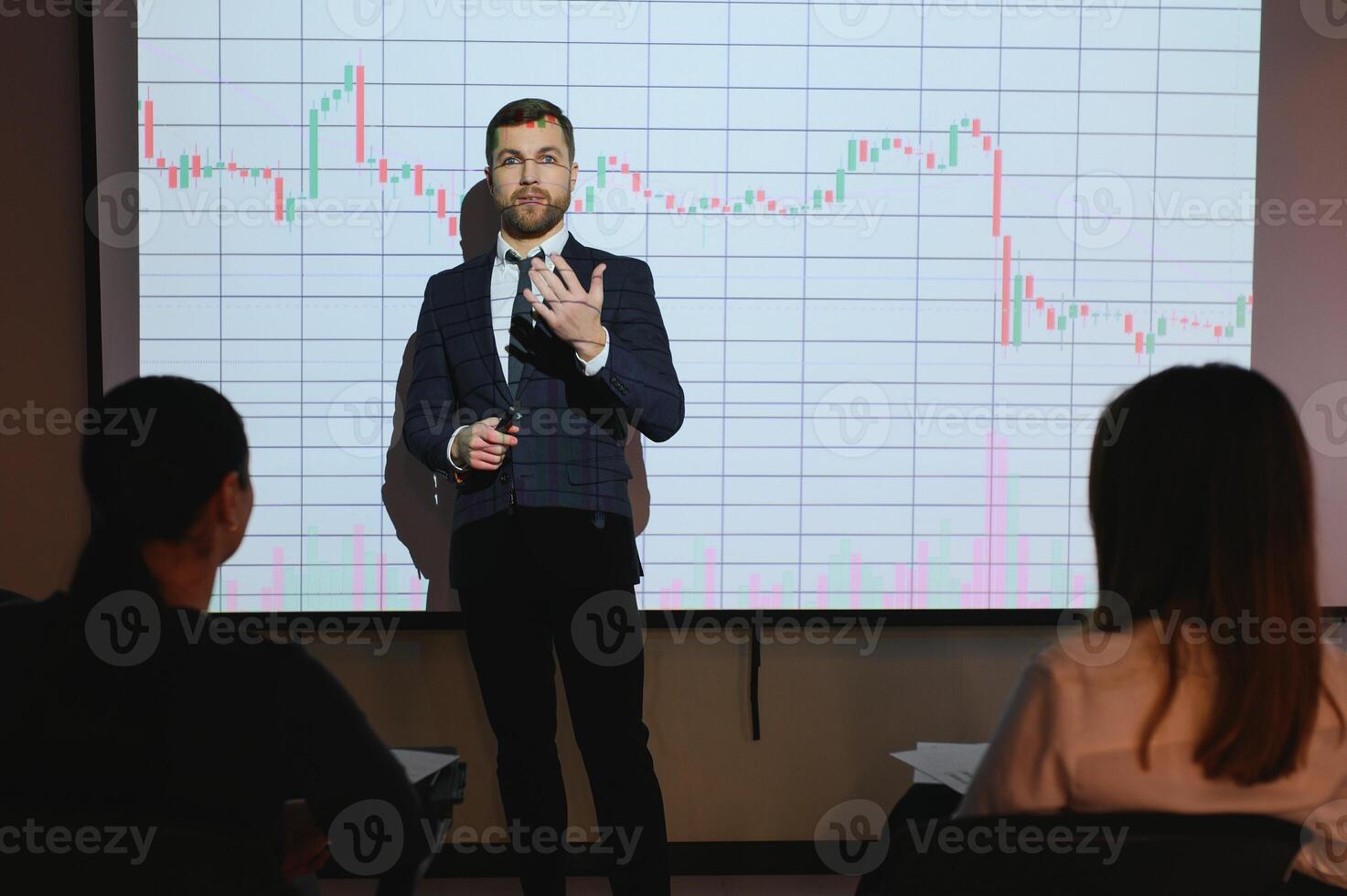 Man is standing near projector and showing graphs and business graphs. photo