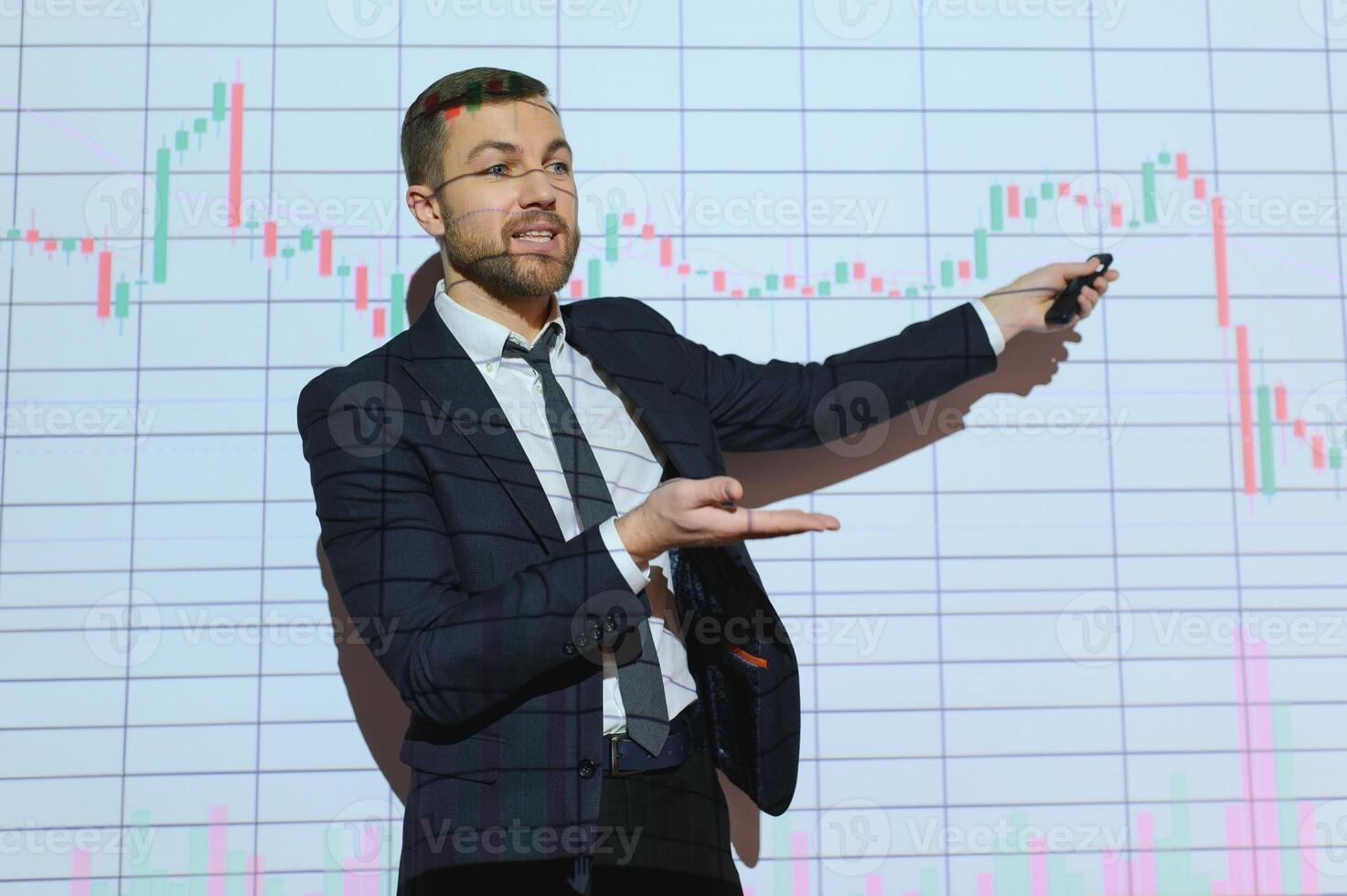 Man is standing near projector and showing graphs and business graphs. photo