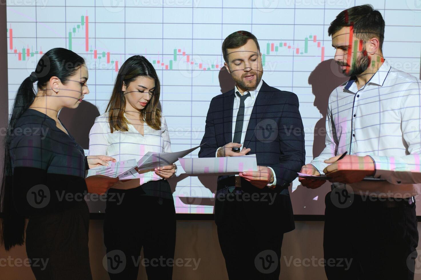 Group of business people working at modern office.Technical price graph, red and blue candlestick chart and stock trading computer screen background. Double exposure. Traders analyzing data photo