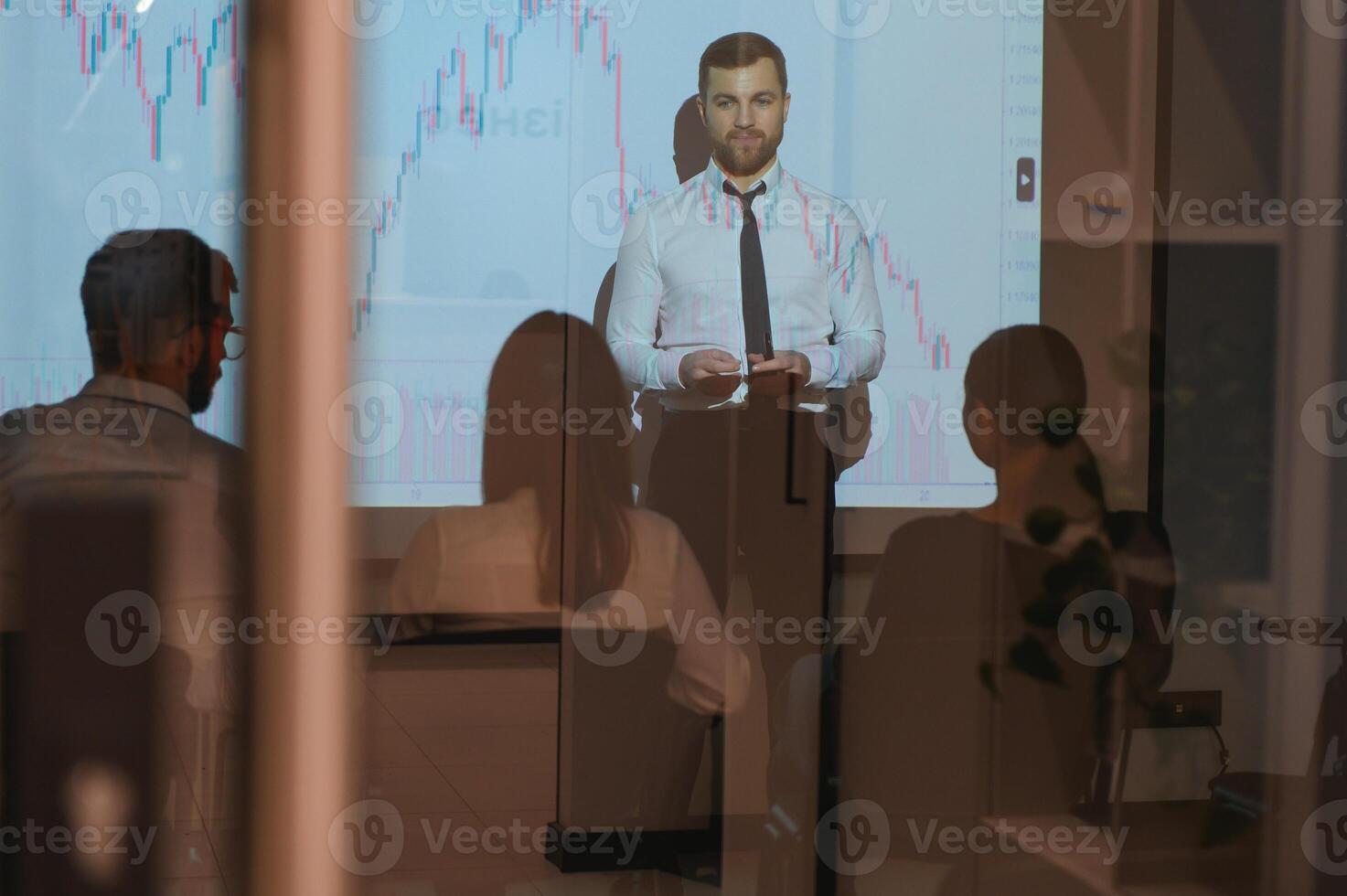 Business Conference Meeting Presentation Businessman does Financial Analysis talks to Group of Businessspeople. Projector Screen Shows Stock Market Data, Investment Strategy, Revenue Growth photo