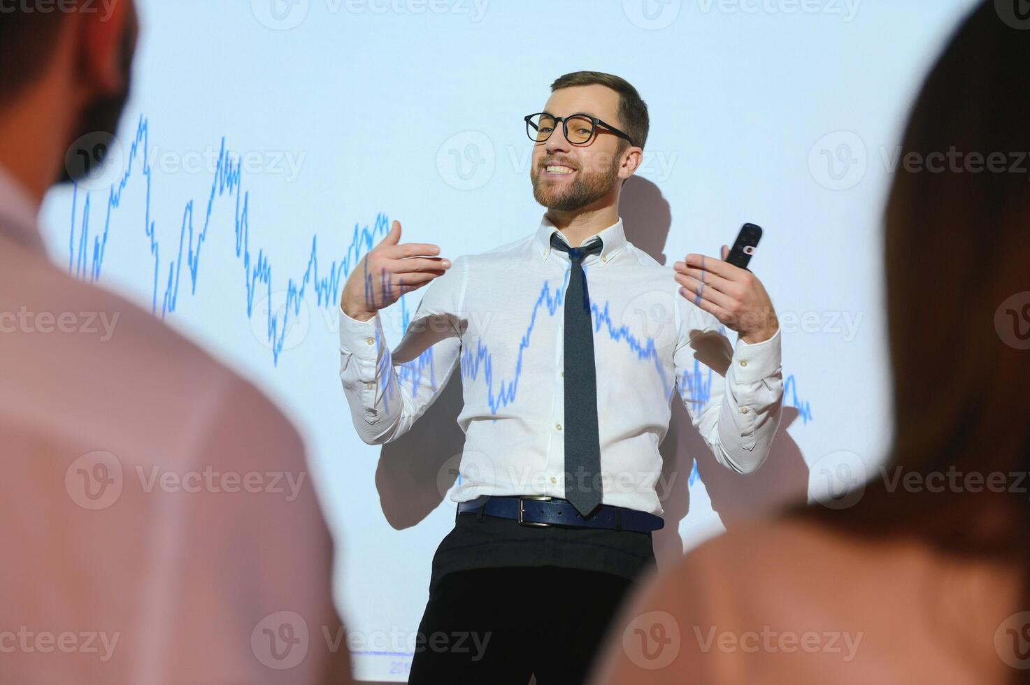 Man is standing near projector and showing graphs and business graphs. photo
