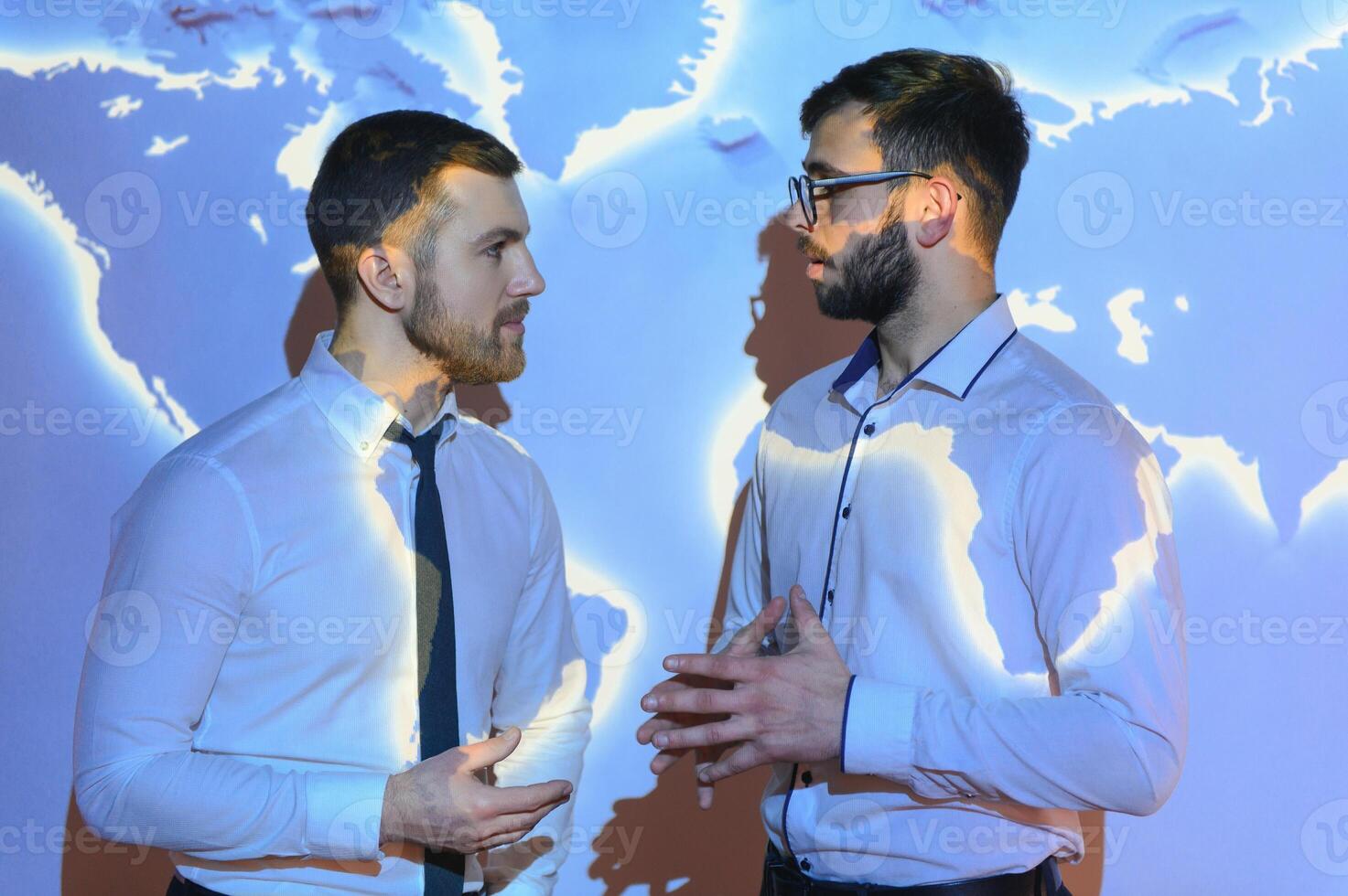 Two Business Colleagues Have Informal Meeting On Stairs Of Office With World Map In Background photo