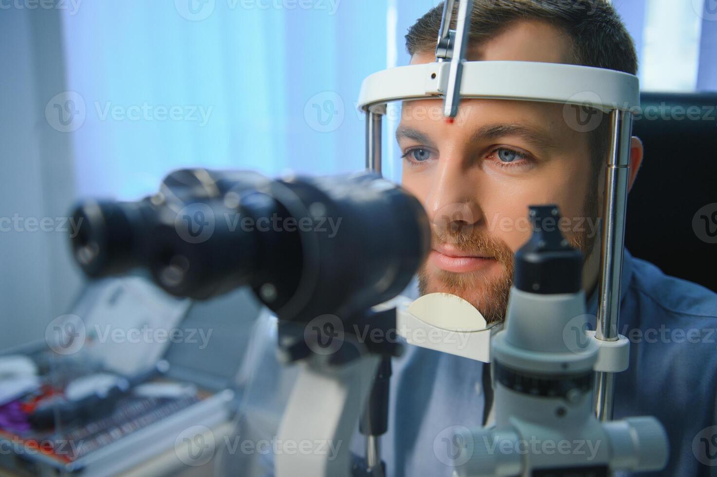 Handsome man getting an eye exam at ophthalmology clinic. Checking retina of a male eye close-up photo