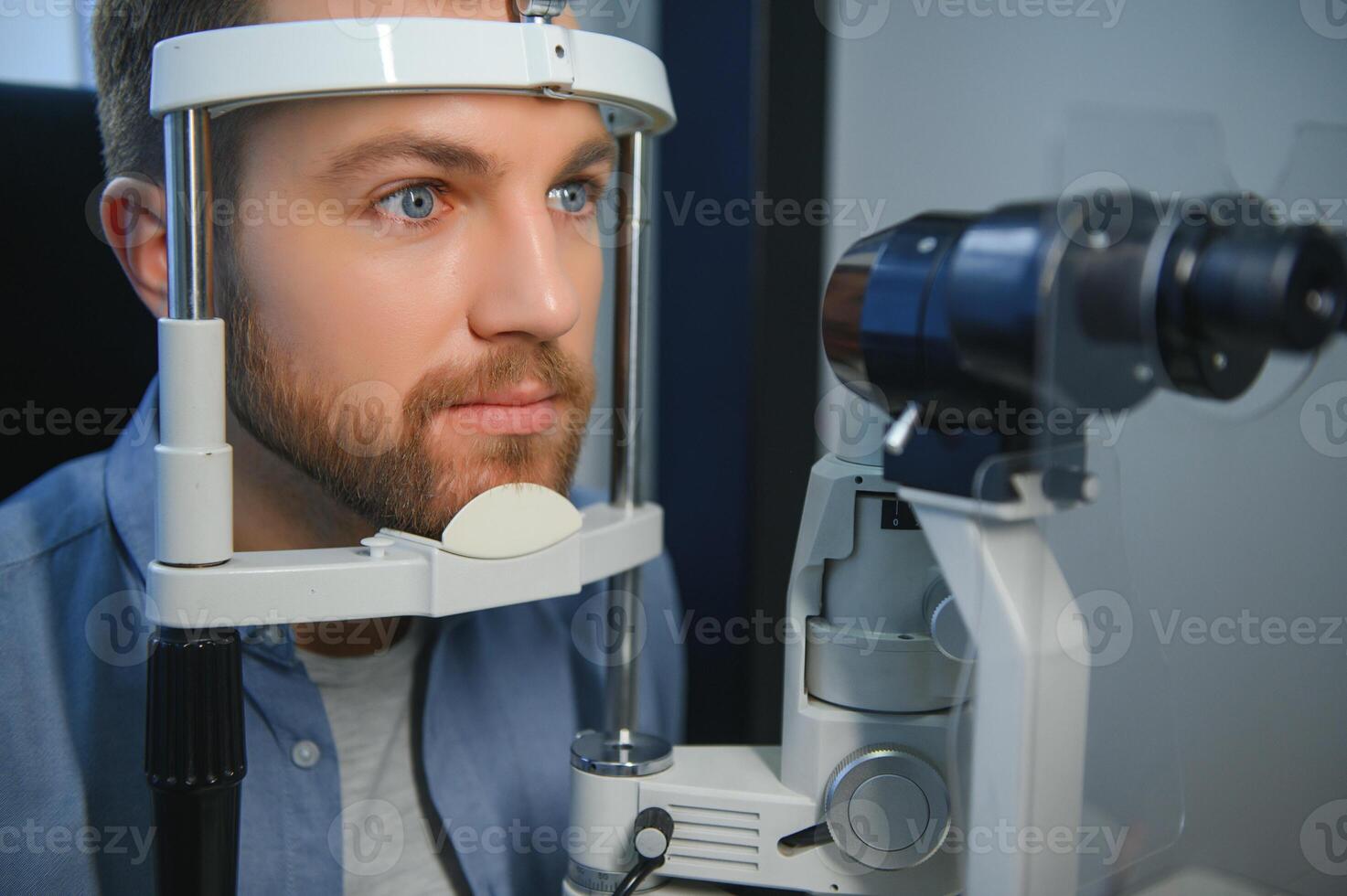 Handsome young man is checking the eye vision in modern ophthalmology clinic. Patient in ophthalmology clinic photo