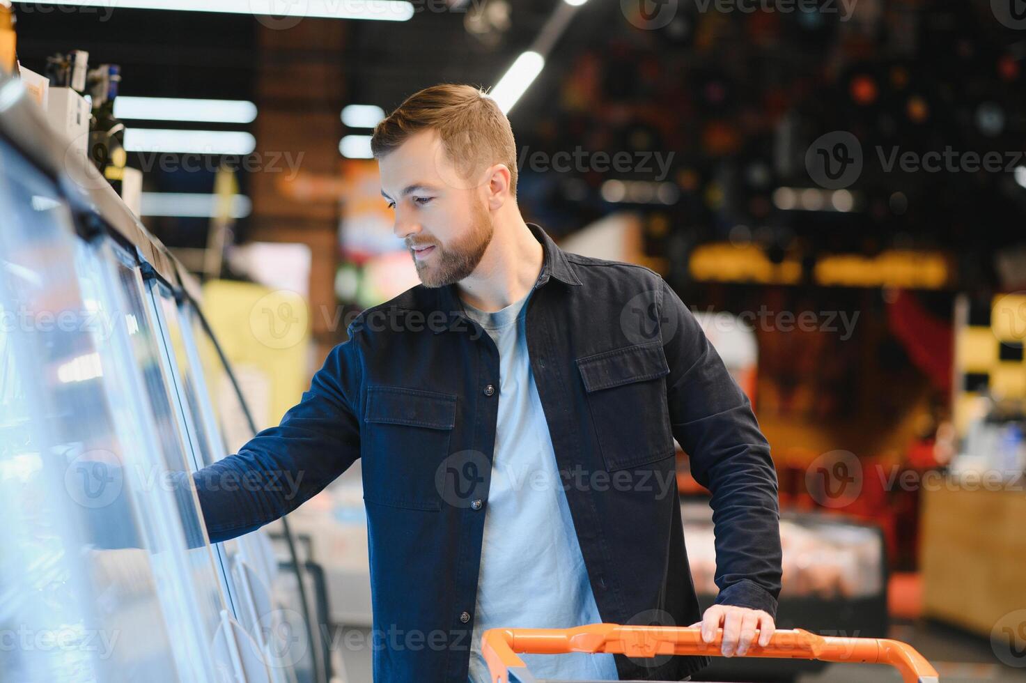 Young man buying groceries at the supermarket. Other customers in background. Consumerism concept. photo