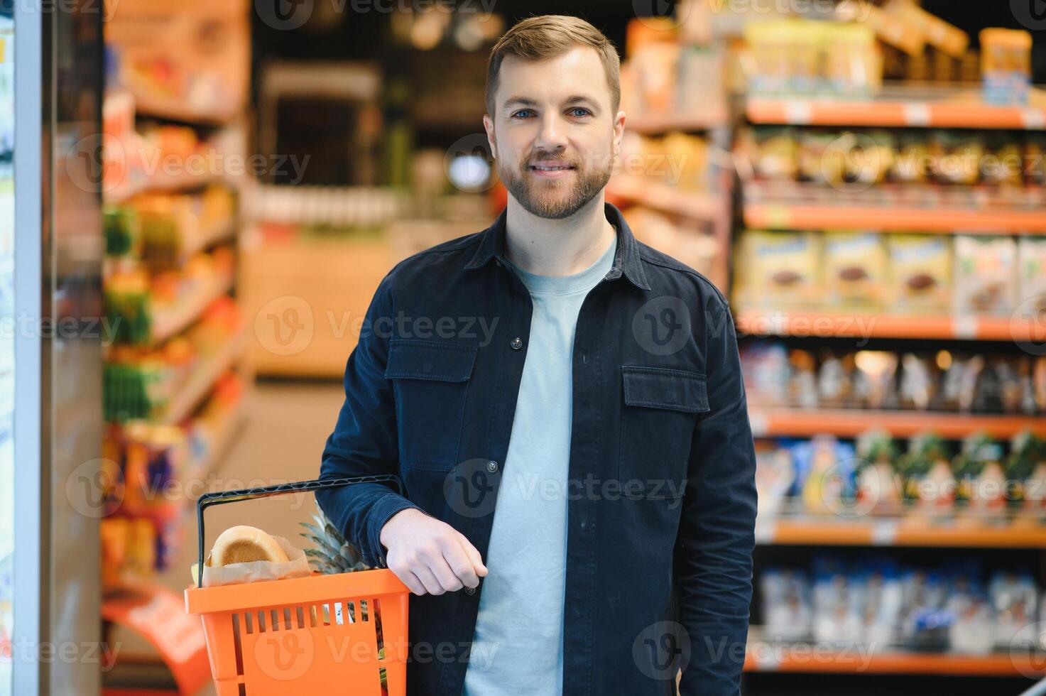 Young man buying groceries at the supermarket. Other customers in background. Consumerism concept. photo