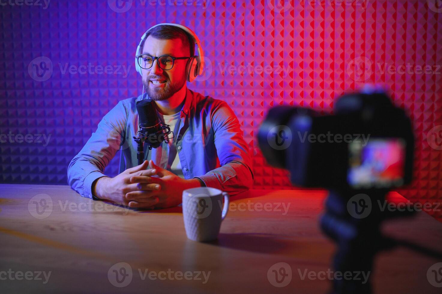 Young man recording or streaming podcast using microphone at his small broadcast studio. Content creator. photo