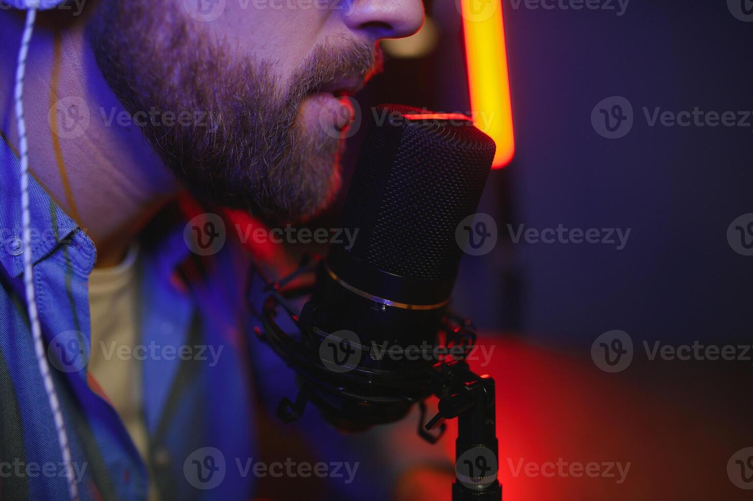 Young man recording or streaming podcast using microphone at his small broadcast studio. Content creator. photo