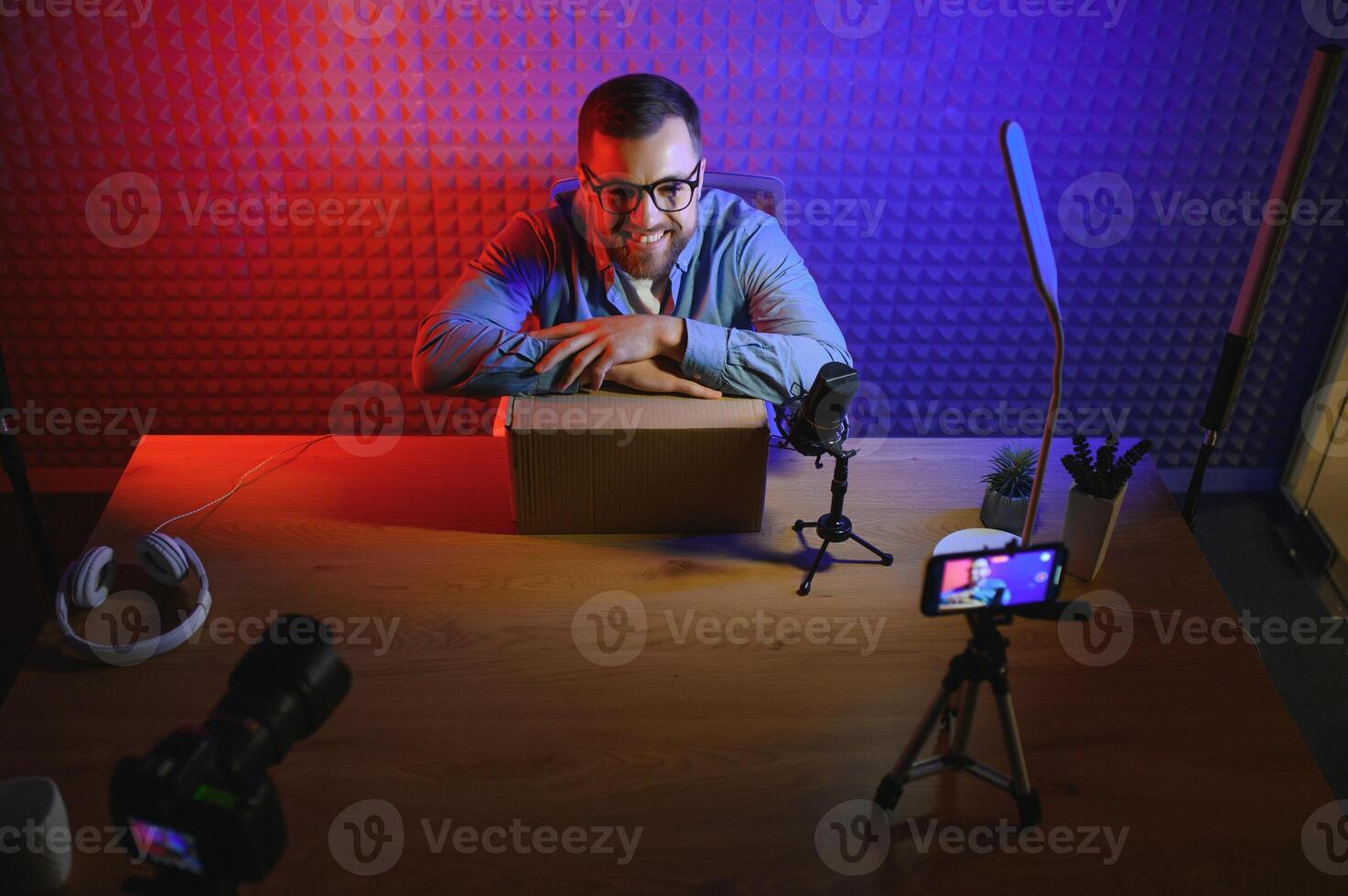 Handsome young man gesturing while unpacking parcel, excited, clenches fists in triumph. Joyful male vlogger. Concept of people and social networks. photo